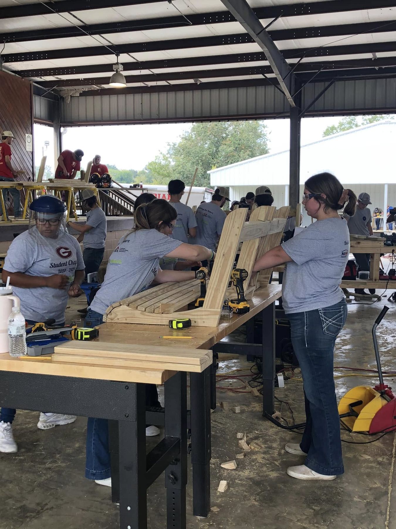 Students assembling workbenches under a pavilion