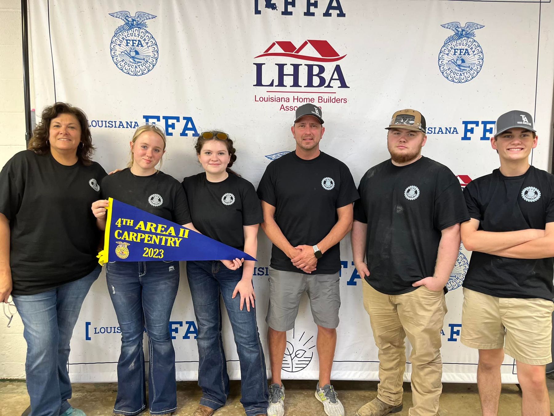 Students and advisors with an area carpentry pennant