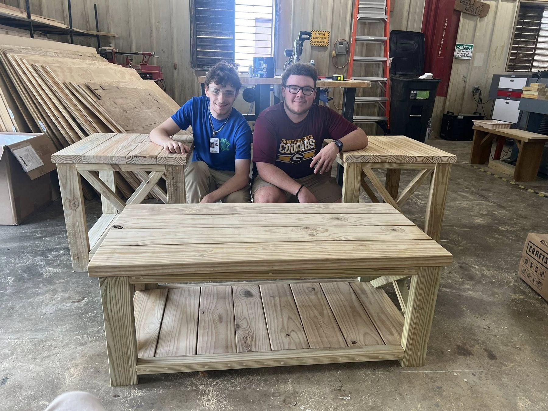 Two students with the bench and table they built