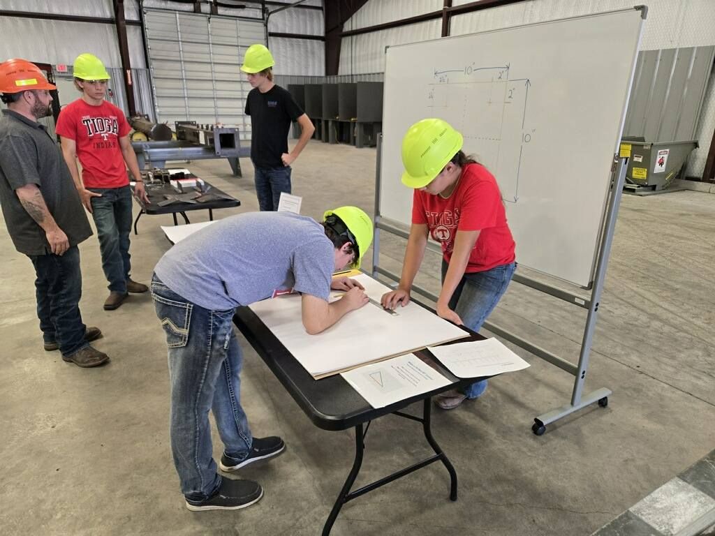 Students in hard hats reviewing blueprints